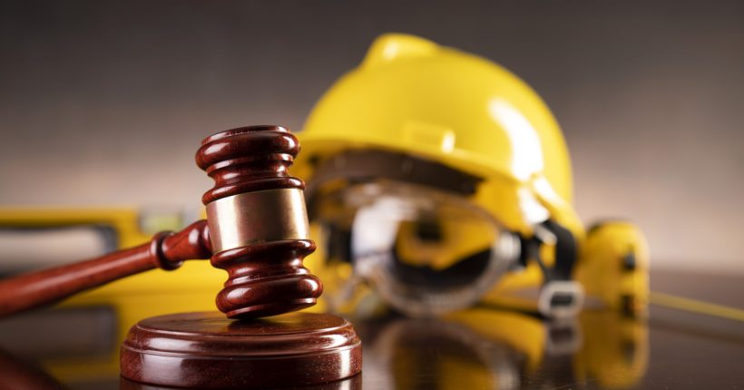 Gavel and yellow crash helmet on the shining lawyer desk.